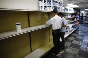 Supermarket staff work next to partially empty shelves of toilet paper in Caracas